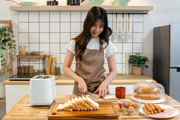 An Asian woman is preparing bread to make a sandwich for breakfast.