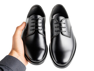 Hand holding a pair of polished black formal shoes for men, sleek and professional, isolated on white background PNG transparent.