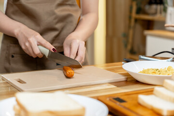 Asian woman preparing sausages to fry for breakfast
