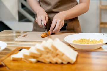Asian woman preparing sausages to fry for breakfast