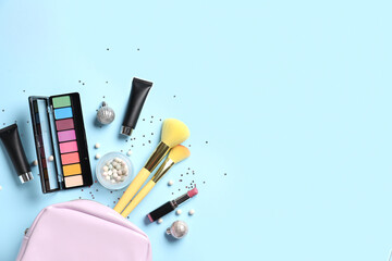 Cosmetic bag with makeup products and Christmas decor on blue background