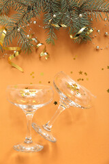 Champagne glasses with Christmas decor on orange background