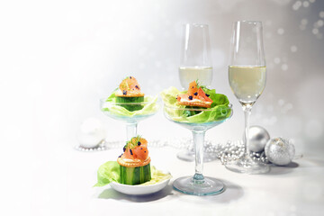 Appetizer from smoked salmon, cucumber, caviar and lettuce, two champagne glasses and holiday decoration, festive snack for Christmas or New Year, copy space, selected focus