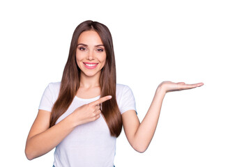 Portrait of lovely millennial holding hand pointing to ads with her index finger isolated over blue...