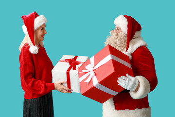 Santa Claus and beautiful mature woman with gift boxes on blue background