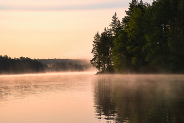 Fototapeta premium Sunrise with fog forming over a lake in Sweden, at dawn. Romantic silence