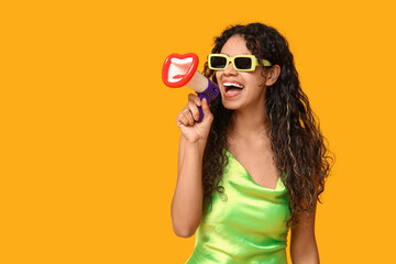 Young African-American woman with funny megaphone on yellow background