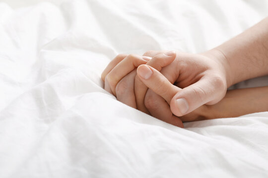 Lovely couple holding hands in bed, closeup. Space for text