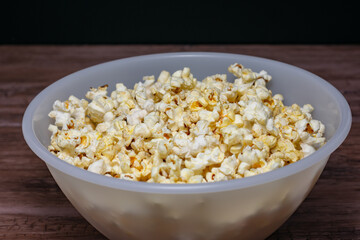 A bowl of popcorn is sitting on a wooden table