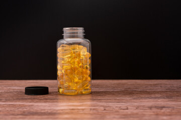 A bottle of yellow pills sits on a wooden table