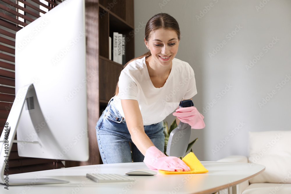 Canvas Prints Young woman cleaning table with rag and spray in office