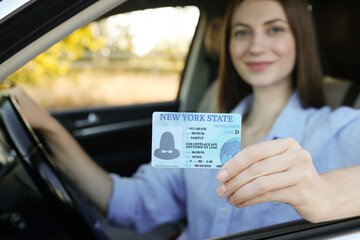 Driving school. Woman with driving license in car, selective focus