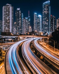 Obraz premium A vibrant cityscape featuring illuminated skyscrapers and dynamic light trails of passing cars at night.