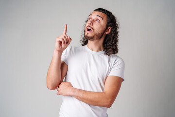 Fototapeta premium Young man with curly hair gestures upward while expressing a thoughtful idea