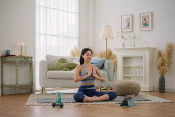 Asian woman wearing sportwear practicing yoga at home studio. Health care and wellness activities.