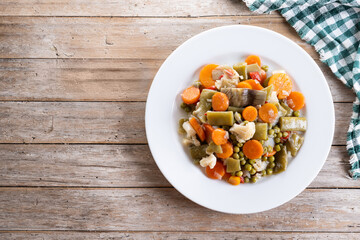 Vegetable stew (menestra de verduras) on wooden table. Top view. Copy space