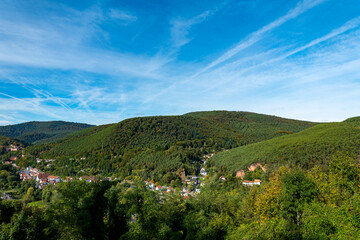 Obraz premium A view of a town nestled in the valley of a green mountain on a sunny day