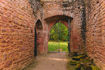 Obraz premium stone archway with a gate in front of it. The gate is open and the archway is dark