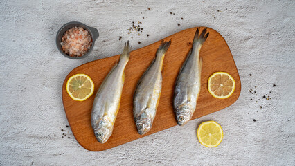 갈색 나무 도마 위에 가지런히 플레이팅된 조기 또는 굴비 