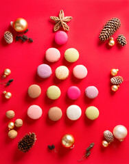 Macaroons on red, french cakes in the shape of a Christmas tree with cones and Christmas balls. Vertical orientation, top view.