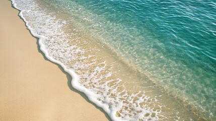 2410_081.aerial view of a soft wave gently washing onto a smooth sandy beach, capturing the delicate contrast between the light beige sand and the clear turquoise water, with white foam forming along