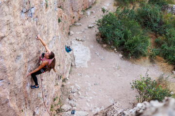 The girl climbs the rock. The climber is training to climb the rock. A strong athlete overcomes a...