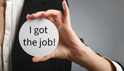 Hand holding a white card with I got the job