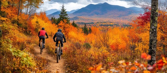 Two mountain bikers ride along a trail through colorful autumn foliage.