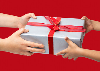 Shot of an unrecognisable mother giving christmas present to daughter with red background.