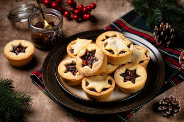 Traditional Christmas Mince pies on a plate sprinkled with sugar decorated with star shape. Also called mincemeat or fruit pie, filled with a mixture of dried fruit, apple, spices and suet.