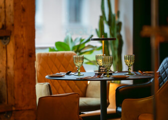 Elegant dinner table. Round served table ready for guests. Round decorated table with empty plate, glasses, forks, napkin. 
