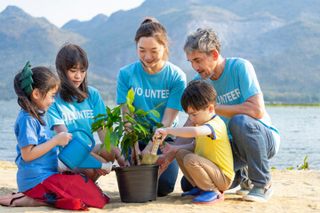 three generations volunteer join planting tree by the river in community to instill awareness in...