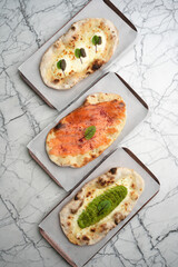 Set of three Pizzas with smoked salmon, avocado, truffle, cheese and pita bread, top view