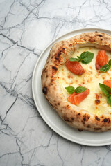 Pizza with salmon, cheese and herbs on a white plate