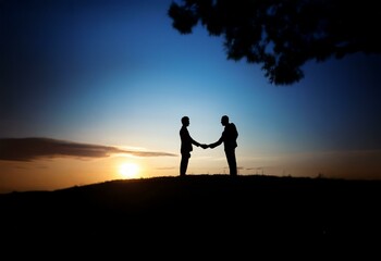 Two silhouettes of people shaking hands in front of a sunset.