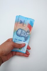 Woman holding several bills worth Rp. 50000, isolate on white background.