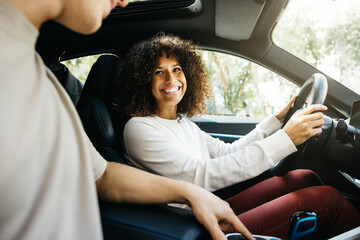 Cheerful couple sits in their electric car, embracing eco-friendly travel. They enjoy the moment...
