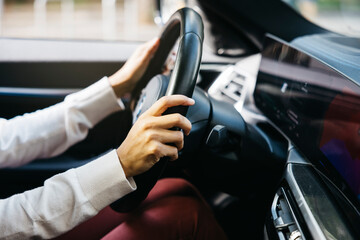 Close-up of a person's hands holding the steering wheel of an electric car, showcasing modern technology and eco-friendly automotive design.