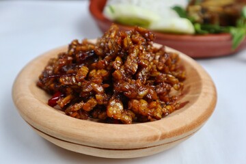 Stir-fried Tempe is a typical Indonesian dish with spices, garlic, shallots, chilies and soy sauce. served on a wooden plate