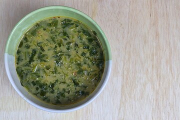 spinach leaf vegetable soup, traditional soup served in a bowl wood background