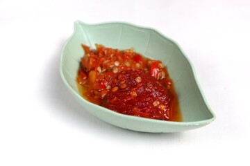 Traditional Indonesian chili sauce namely crushed chilies with shrimp paste, garlic, shallots and spices served in a bowl isolated on a white background
