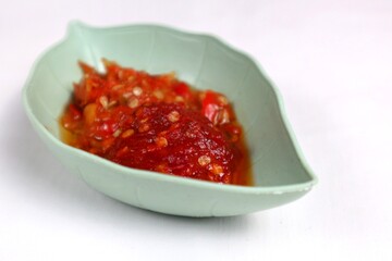Traditional Indonesian chili sauce namely crushed chilies with shrimp paste, garlic, shallots and spices served in a bowl isolated on a white background