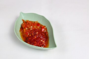 Traditional Indonesian chili sauce namely crushed chilies with shrimp paste, garlic, shallots and spices served in a bowl isolated on a white background