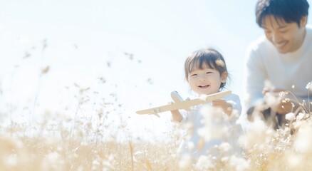 明るい陽光の中で飛行機の模型を持って遊ぶ幼児と父親