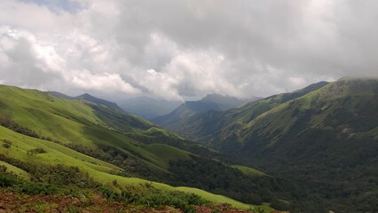 Obraz premium Scenic view of lush green mountains under a cloudy sky