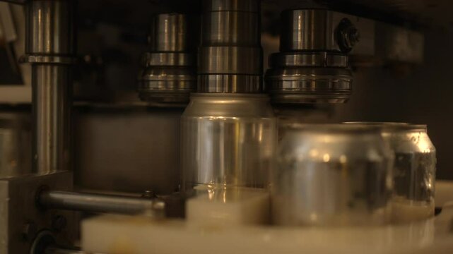 Closeup footage of a can seamer machine working on beer cans in a brewery
