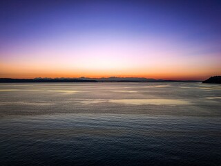 Stunning sunset over a calm sea with a gradient sky transitioning from orange to blue.