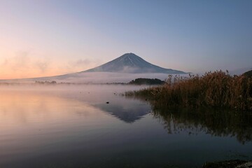 Mount Fuji with mist over a calm lake during sunrise