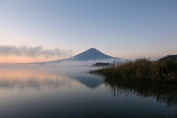 Obraz premium Mount Fuji landscape at sunrise with mist over the lake.