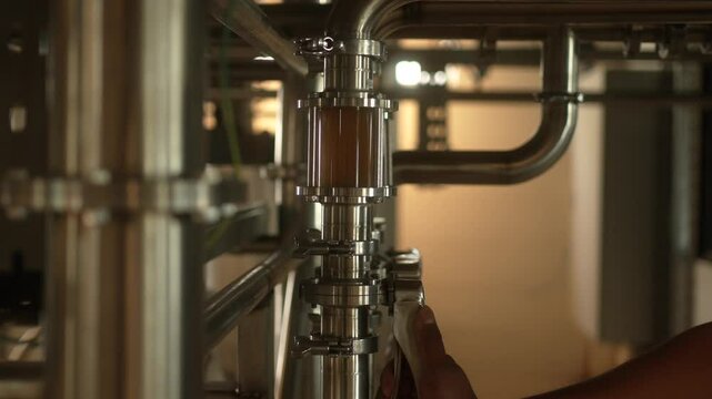Worker pumping the beer in the pipeline system in a brewery - process of alcohol liquor production